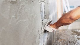 closeup hand of worker plastering cement at wall in construction